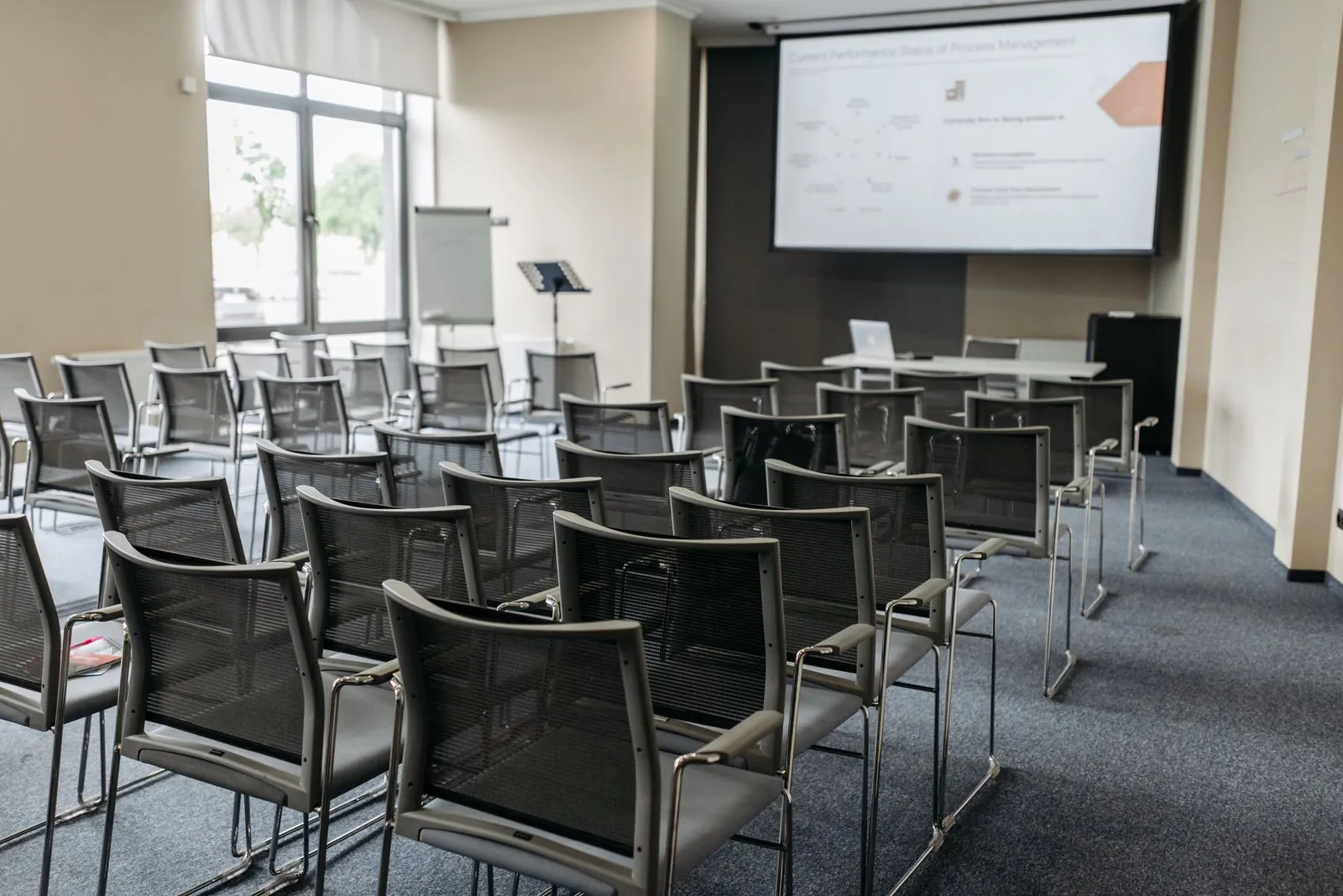 Empty conference room with rows of chairs and a projector screen. Photo by Pavel Danilyuk.